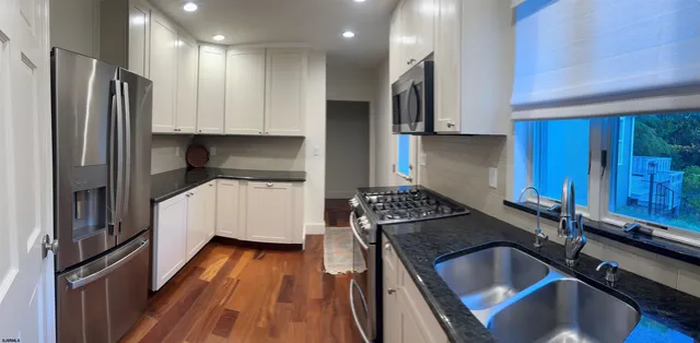 a kitchen that has a sink stainless steel appliances wooden floor and a counter top space