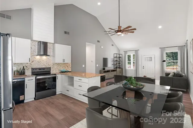 a open kitchen with stainless steel appliances granite countertop a stove white cabinets a dining table and chairs