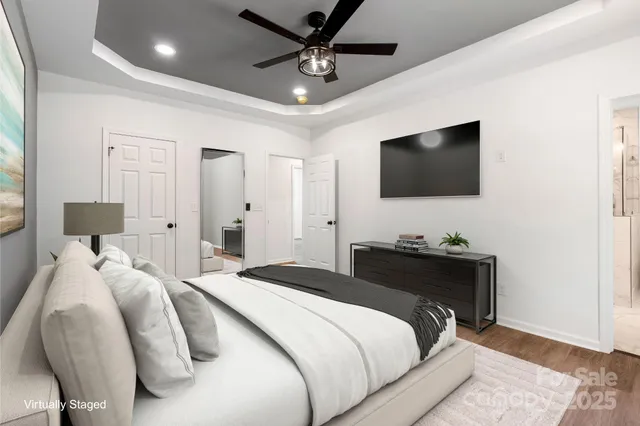 a bedroom with a bed a flat screen tv and a chandelier