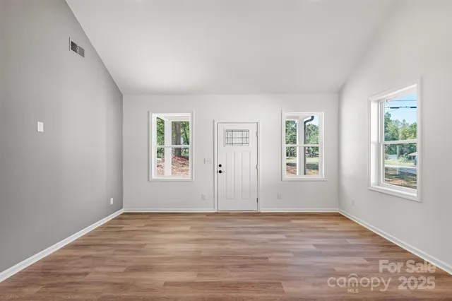 an empty room with wooden floor and windows