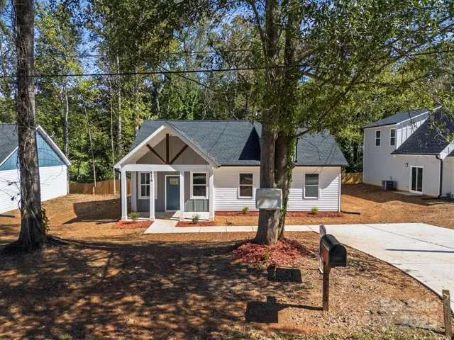 a front view of a house with large trees