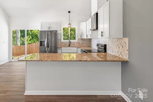 a large kitchen with granite countertop a sink a window and stainless steel appliances