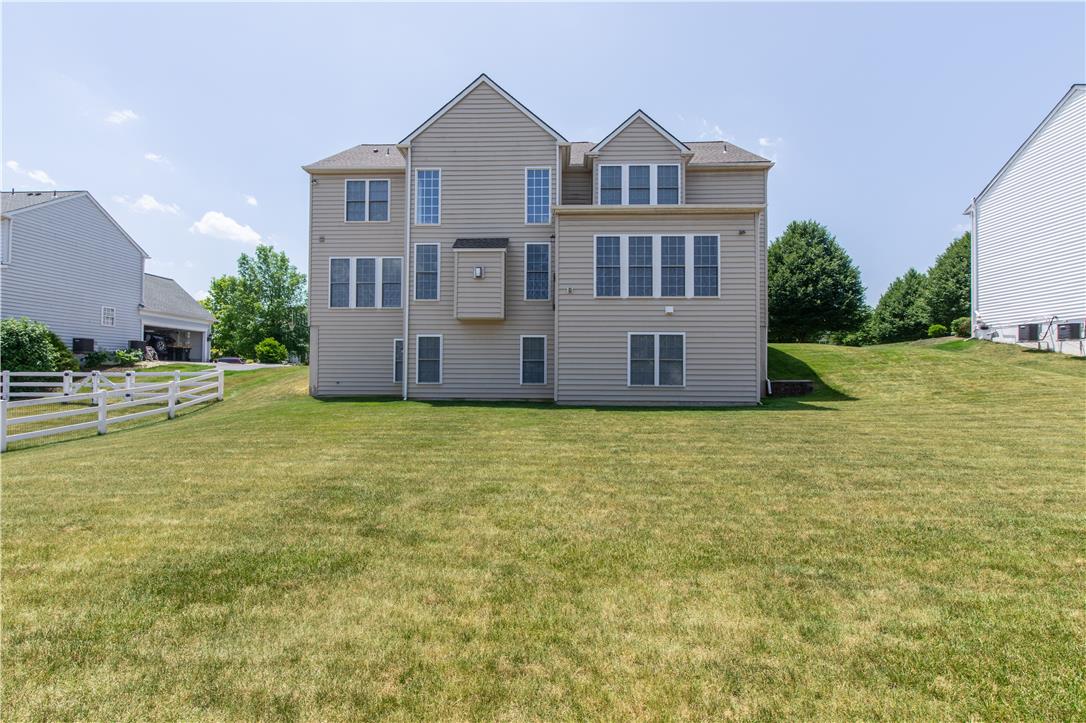 1709 Travers Road Breinigsville, PA 18031 - Photo 49 of 55 A well-maintained lawn extends to the rear facade of a residence, framed by a white fence and neighboring properties.