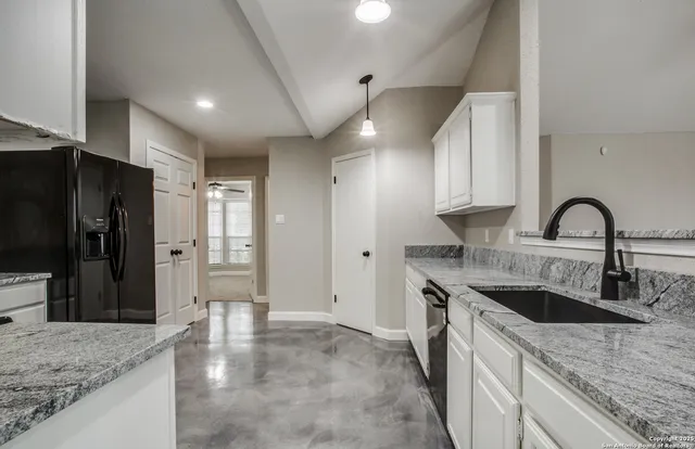 a kitchen with granite countertop a refrigerator and a sink