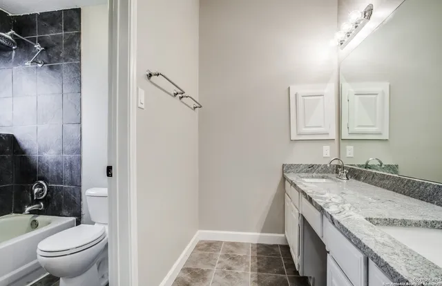 a bathroom with a granite countertop sink toilet and shower