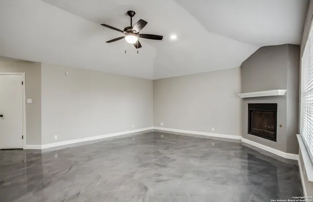 an empty room with chandelier fan and windows