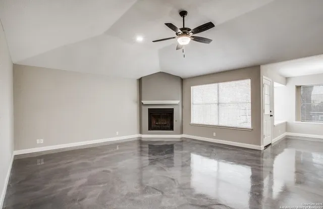 an empty room with windows and ceiling fan