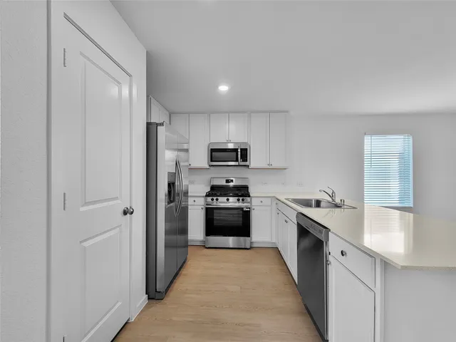 a large kitchen with cabinets stainless steel appliances and a window