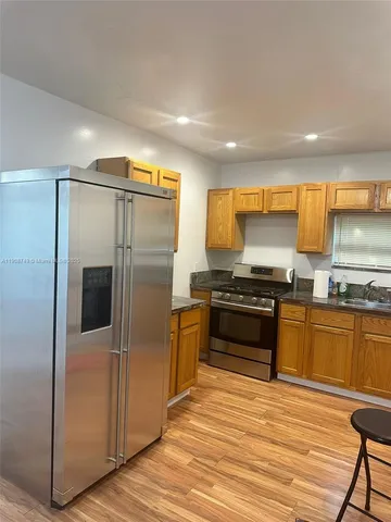 a kitchen with granite countertop a refrigerator and a stove top oven