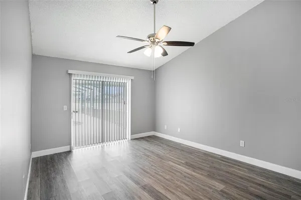 an empty room with wooden floor fan and windows