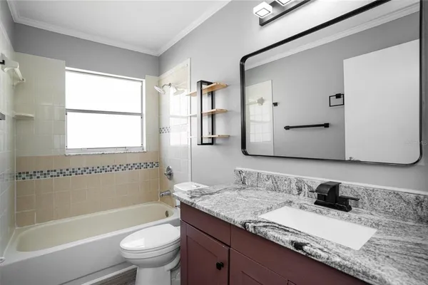 a bathroom with a granite countertop sink toilet mirror and bathtub