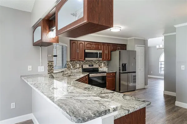 a kitchen with stainless steel appliances kitchen island granite countertop a refrigerator a stove and a sink