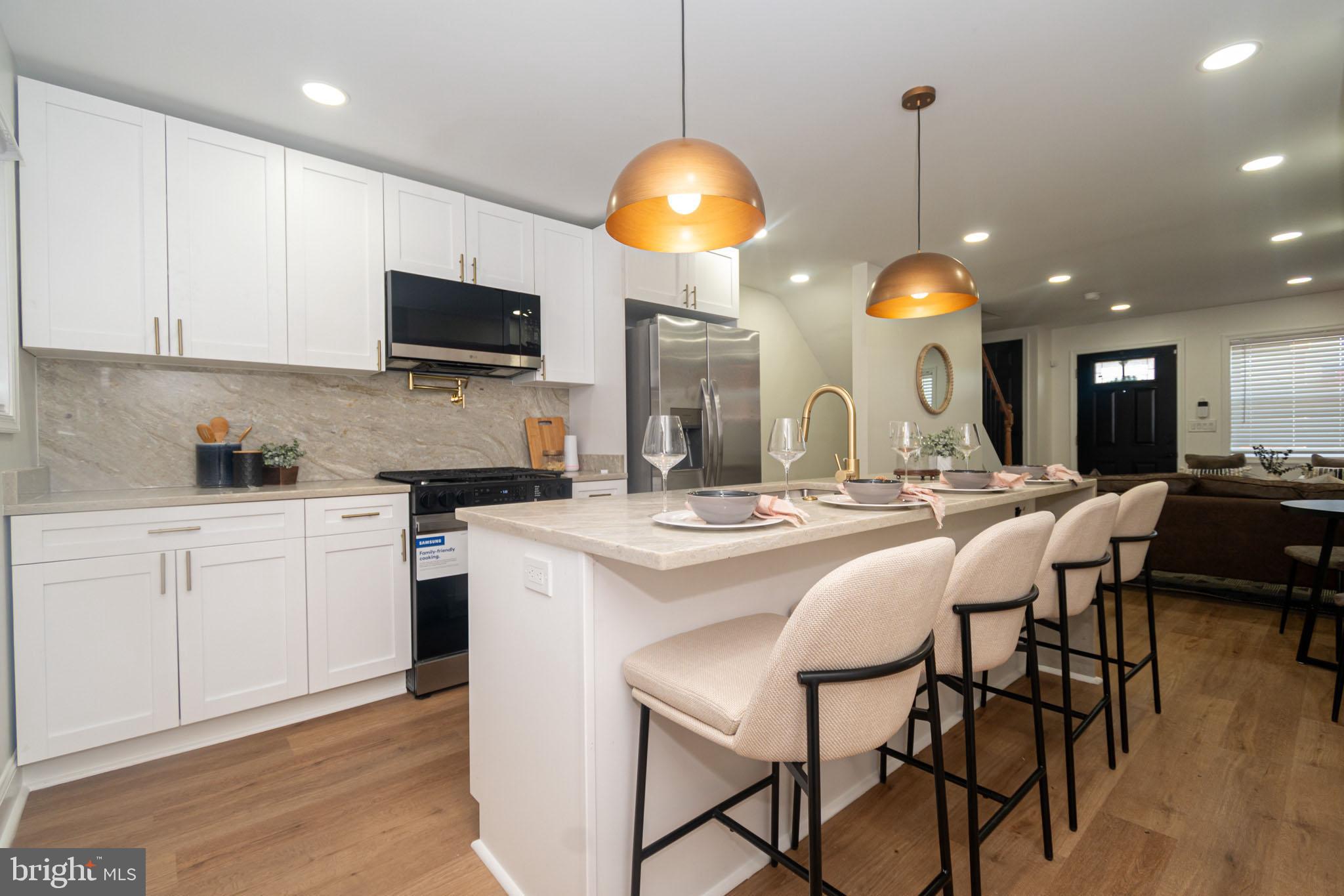2560 Cecil Avenue Baltimore, MD 21218 - Photo 4 of 11 a kitchen with stainless steel appliances kitchen island granite countertop a sink a stove and a dining table with chairs