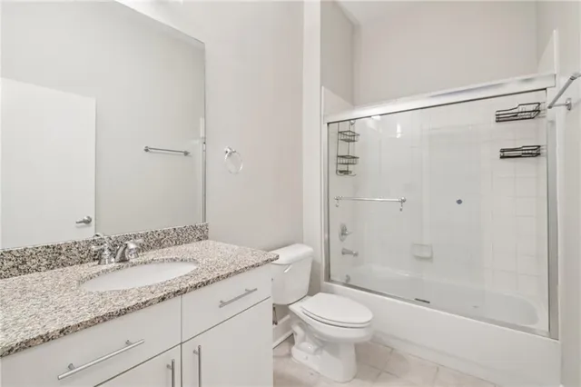a bathroom with a granite countertop sink a toilet and shower
