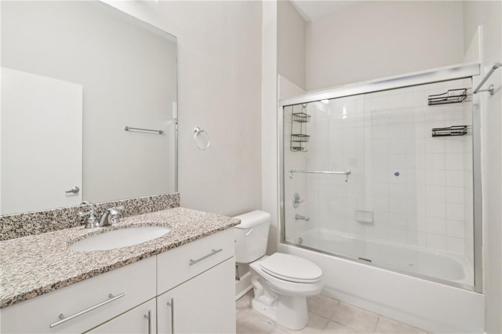 384 Ralph McGill Boulevard Northeast, Unit 105 Atlanta, GA 30312 - Photo 18 of 29 a bathroom with a granite countertop sink a toilet and shower