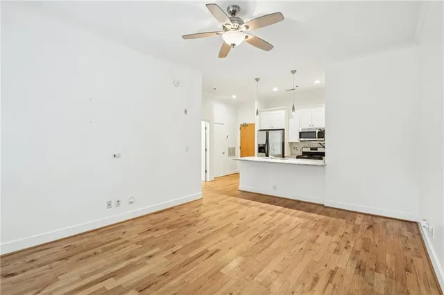 a view of kitchen and empty room with wooden floor