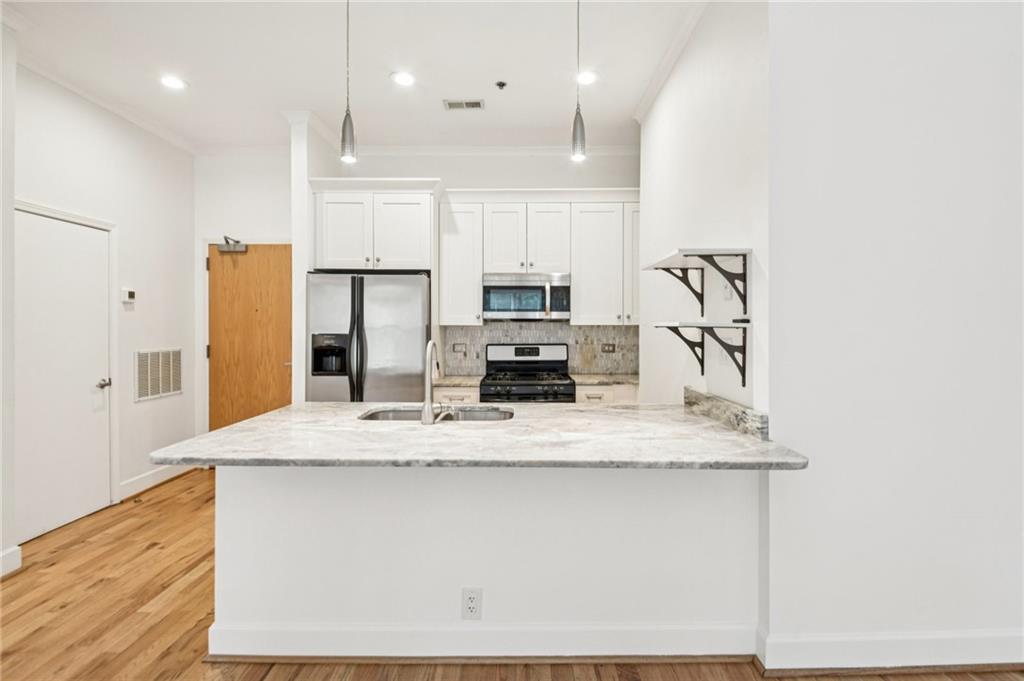 384 Ralph McGill Boulevard Northeast, Unit 105 Atlanta, GA 30312 - Photo 5 of 29 a large kitchen with stainless steel appliances granite countertop a stove a refrigerator a sink and a microwave