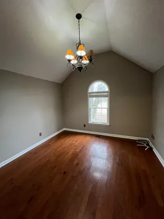 a view of a room with wooden floor chandelier and a window