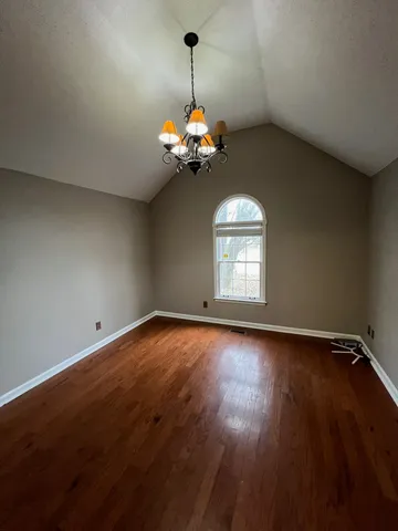 a view of a room with wooden floor chandelier and a window