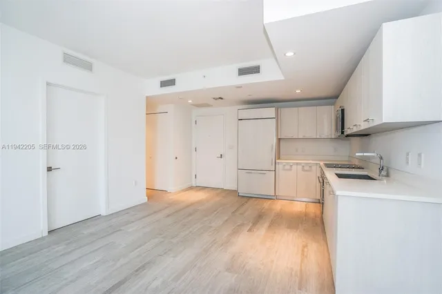 a kitchen with wooden floors and white cabinets