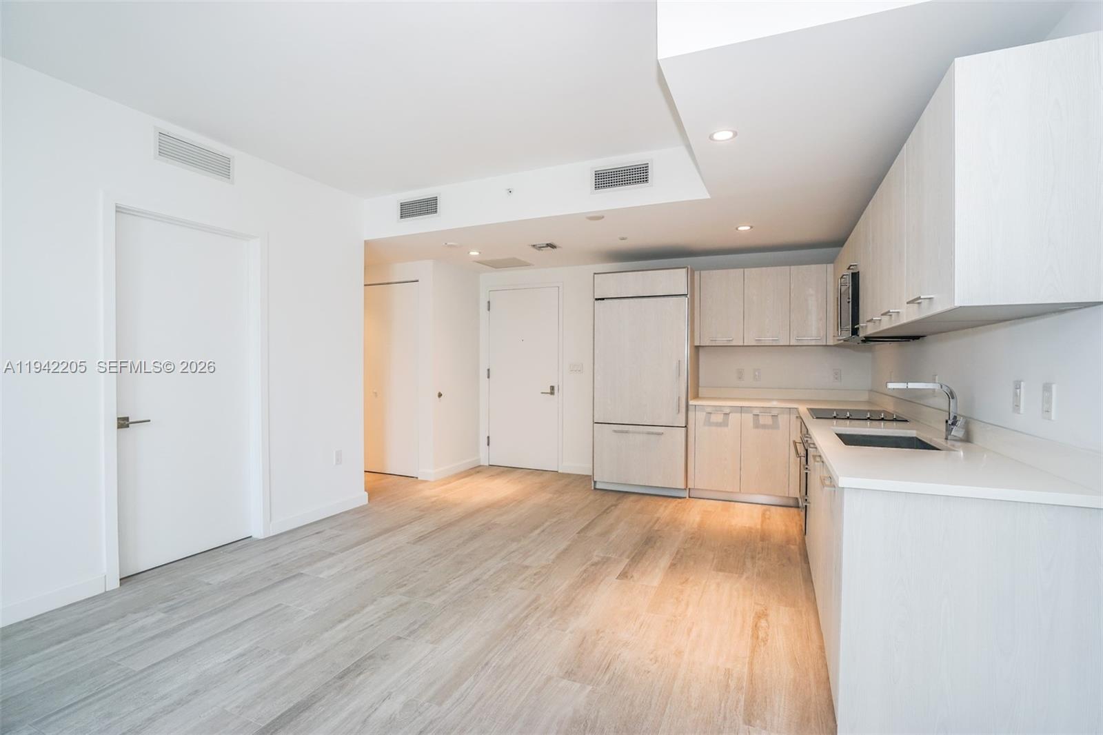 55 Southwest 9th Street, Unit 1407 Miami, FL 33130 - Photo 2 of 24 a kitchen with wooden floors and white cabinets