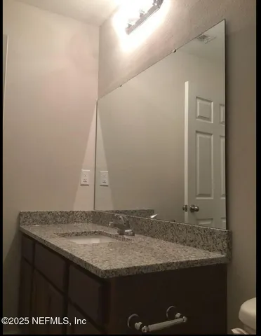 a bathroom with a granite countertop sink and a mirror
