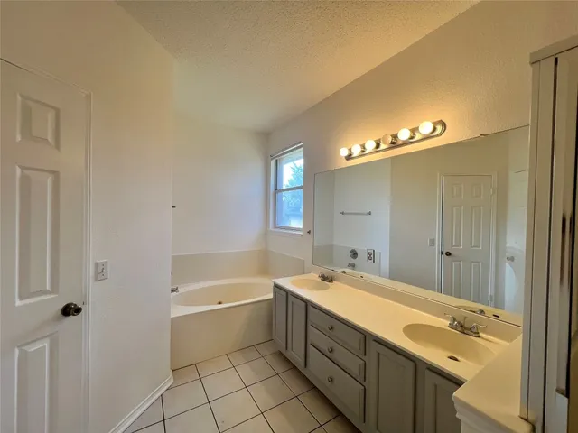 a spacious bathroom with a double vanity sink a mirror and a bathtub