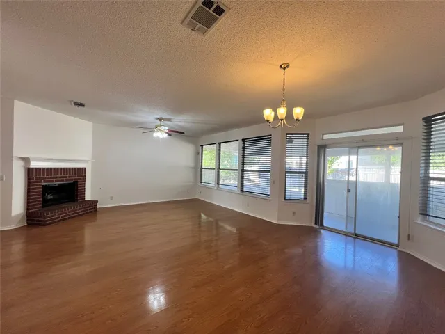a view of an empty room with a fireplace and wooden floor