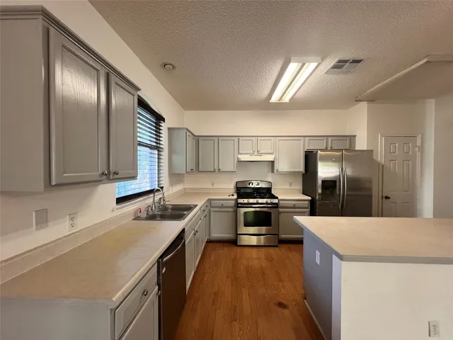 a kitchen with stainless steel appliances granite countertop a sink stove and refrigerator