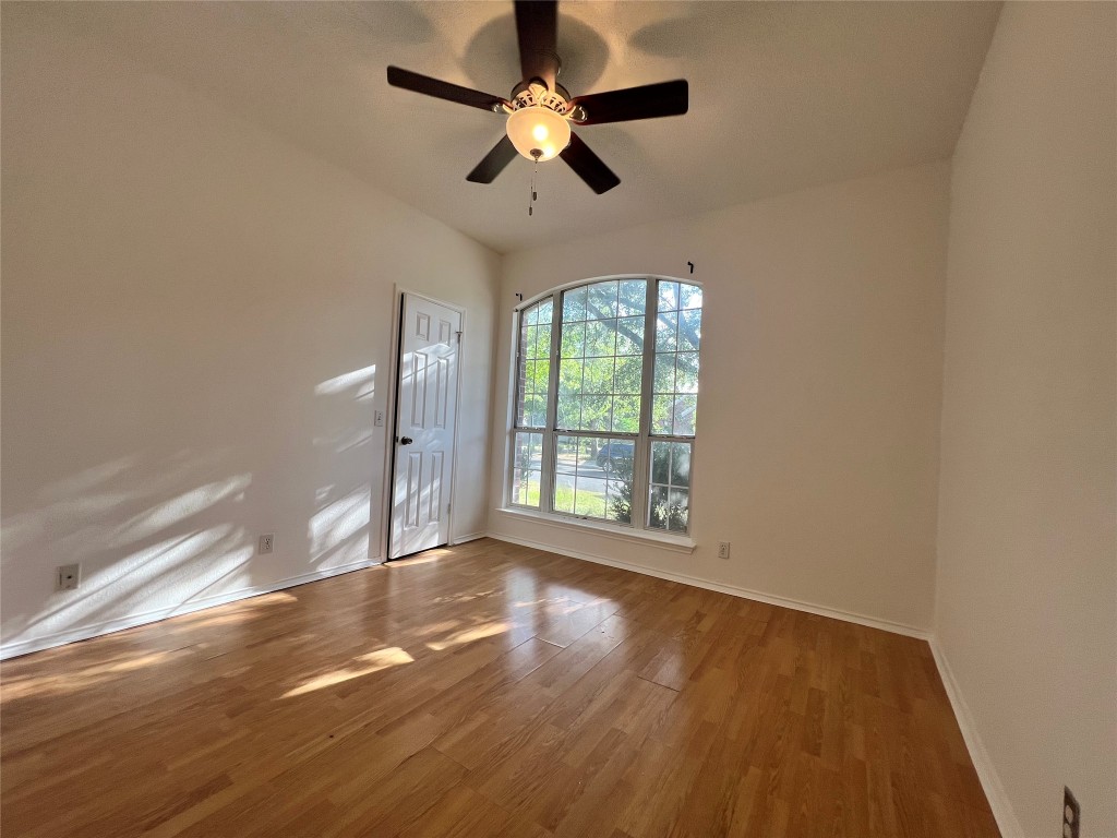 1525 Natural Bridge Lane Pflugerville, TX 78660 - Photo 8 of 15 an empty room with wooden floor fan and windows