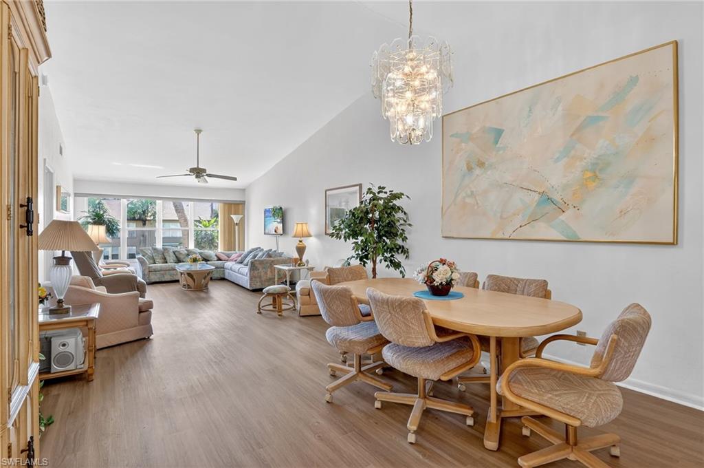 4210 Looking Glass Lane, Unit 4210 Naples, FL 34112 - Photo 6 of 20 a dining room with furniture a chandelier and wooden floor