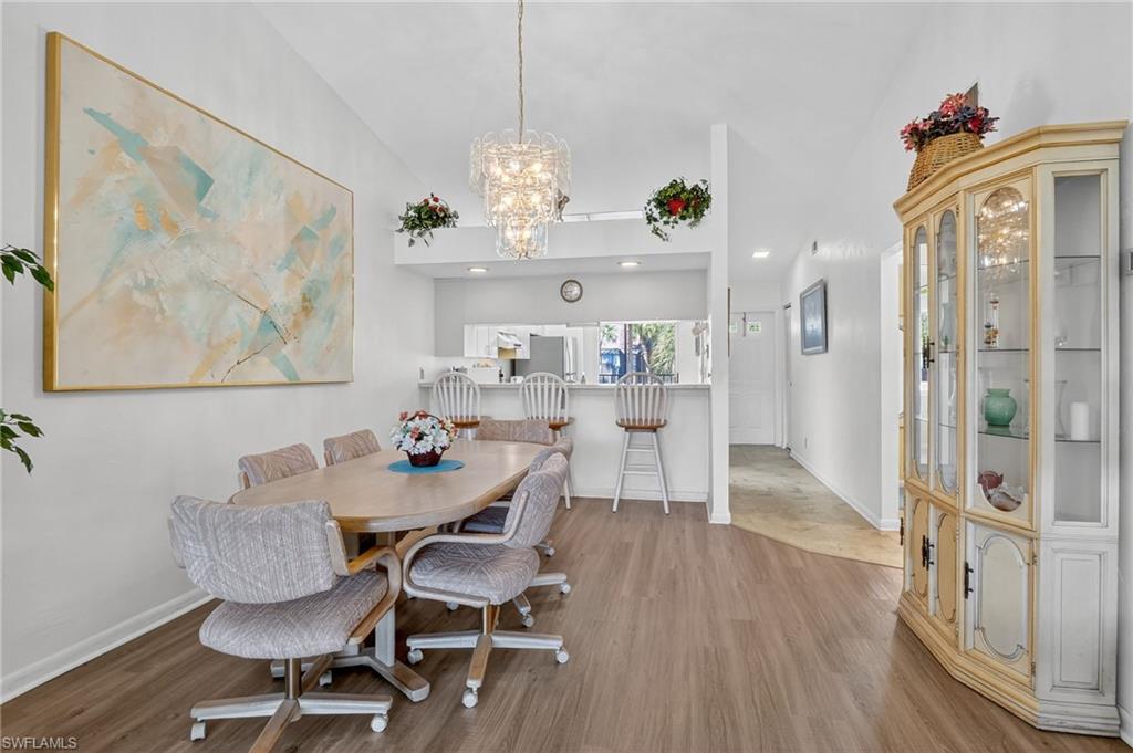 4210 Looking Glass Lane, Unit 4210 Naples, FL 34112 - Photo 7 of 20 a view of a dining room with furniture wooden floor and a chandelier