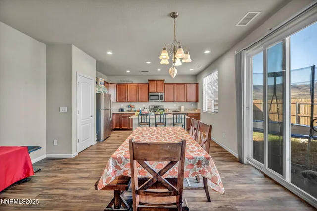 a view of a dining room and livingroom with furniture wooden floor a rug a fireplace and a chandelier