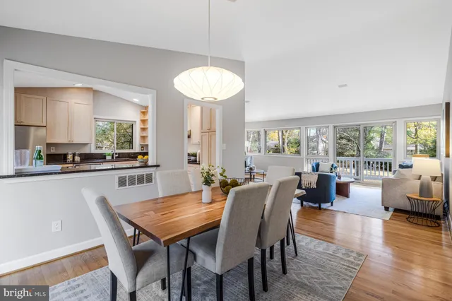 a kitchen with stainless steel appliances granite countertop white cabinets a sink a stove a refrigerator and island with wooden floor