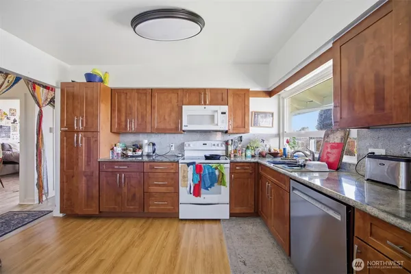 a kitchen with stainless steel appliances granite countertop a stove a sink dishwasher and a refrigerator with wooden floor