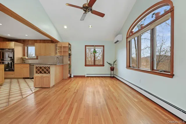 a view of an empty room with window and wooden floor
