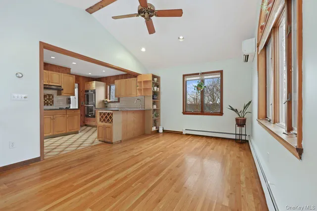 a view of a kitchen with wooden floor a ceiling fan and windows