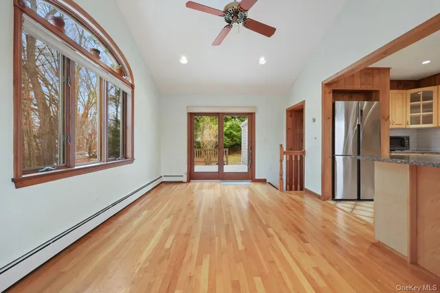 a view of an empty room with a window and wooden floor