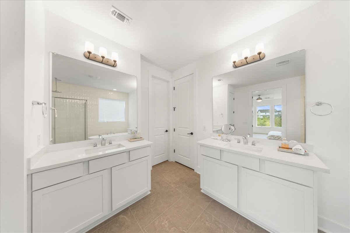 8700 Olmsted Way Austin, TX 78744 - Photo 20 of 40 Ensuite bathroom with a shower stall, two vanities, light tile patterned flooring, and a ceiling fan