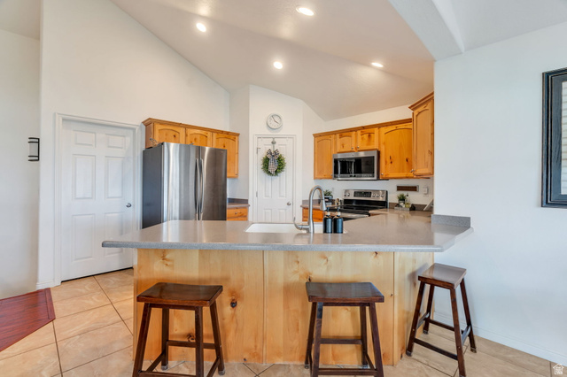 1602 Renaissance Way Springville, UT 84663 - Photo 11 of 42 Kitchen with a peninsula, a breakfast bar, stainless steel appliances, lofted ceiling, and recessed lighting