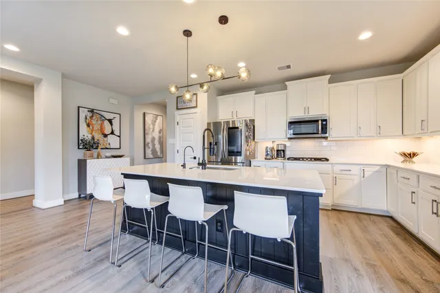 a kitchen with kitchen island granite countertop a dining table chairs and white cabinets with wooden floor