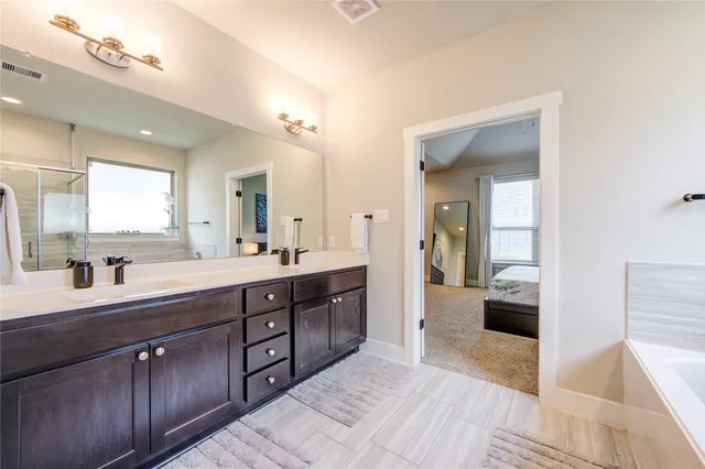 a spacious en suite bathroom with double vanity and a mirror