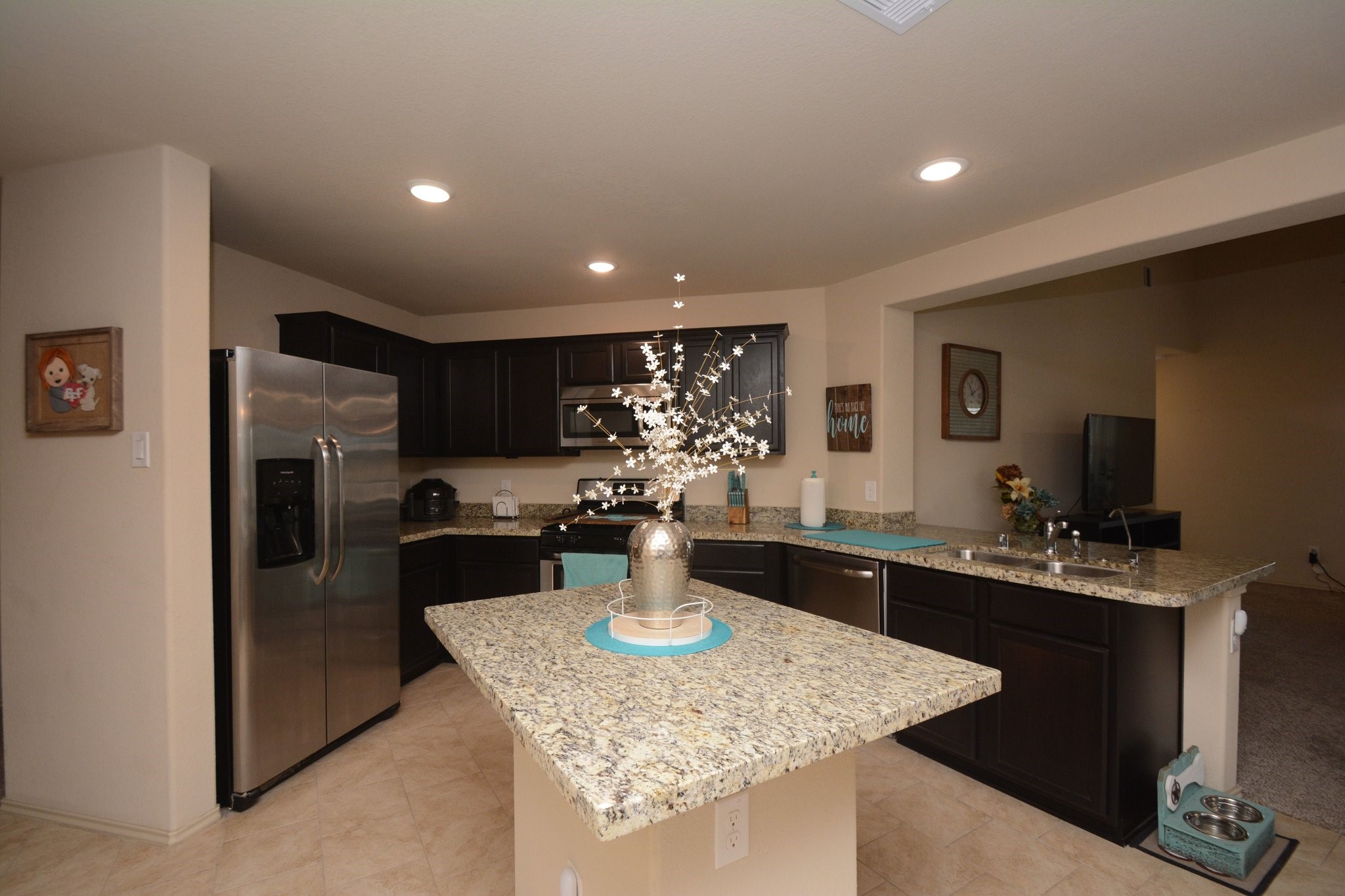 23318 Dukes Run Drive Spring, TX 77373 - Photo 6 of 41 This kitchen features modern stainless steel appliances, dark wood cabinetry, and granite countertops. It has a spacious island with decorative elements, recessed lighting, and an open layout connecting to the living area.