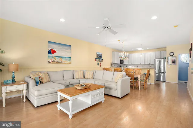 a dining area with stainless steel appliances kitchen island granite countertop a dining table chairs and a refrigerator