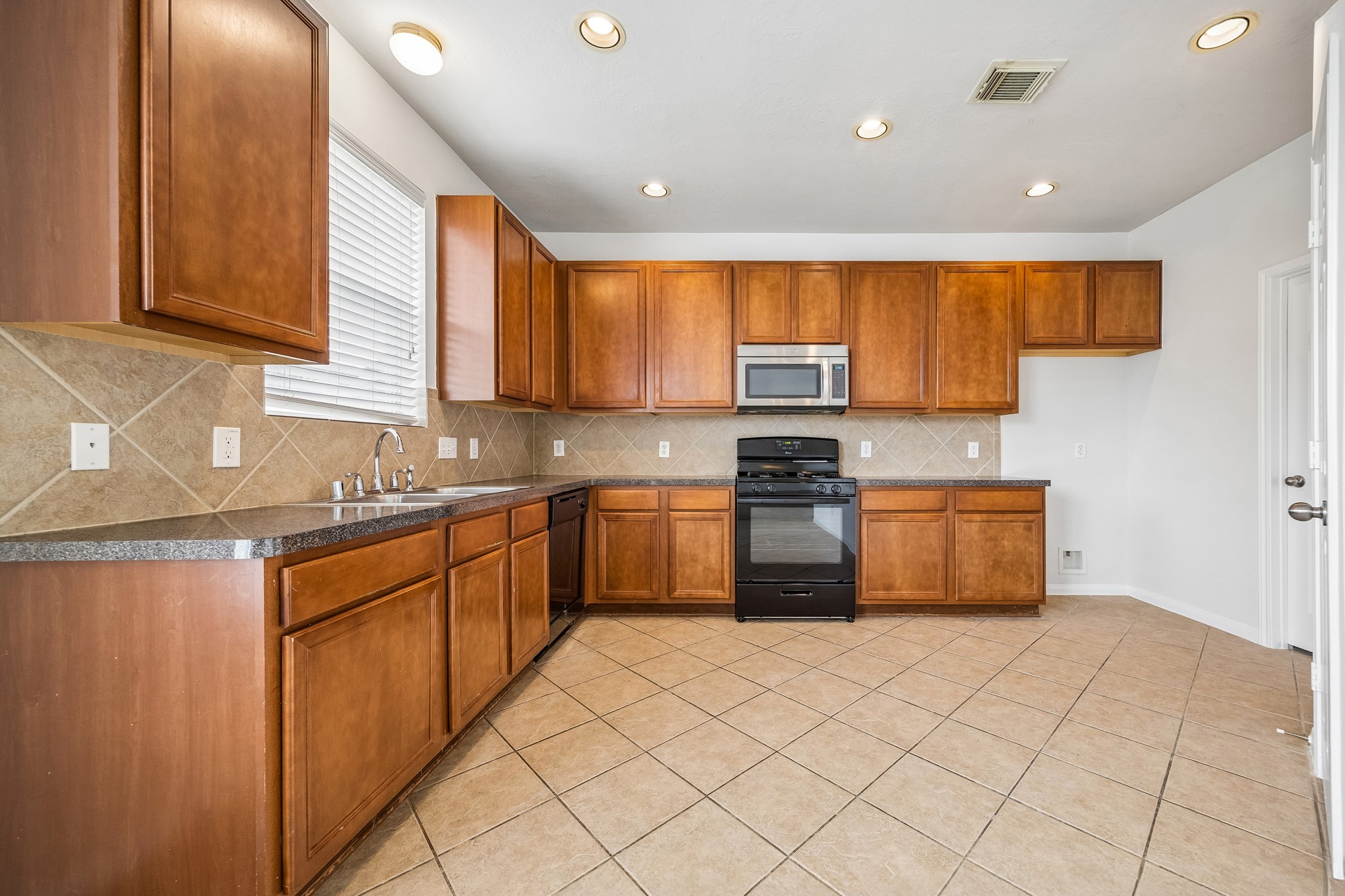 25211 Hazel Ranch Drive Katy, TX 77494 - Photo 3 of 10 a kitchen with stainless steel appliances granite countertop a stove a sink a microwave a counter top space and cabinets