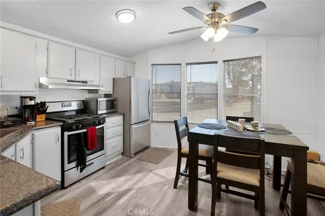 a kitchen with stainless steel appliances kitchen island granite countertop a dining table and chairs