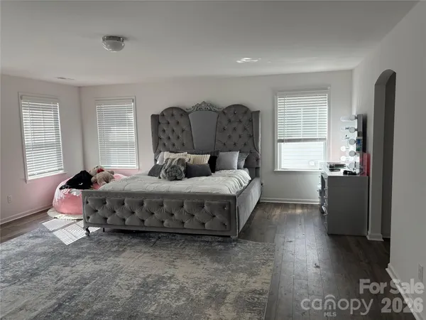 a spacious bedroom with a bed and wooden floor