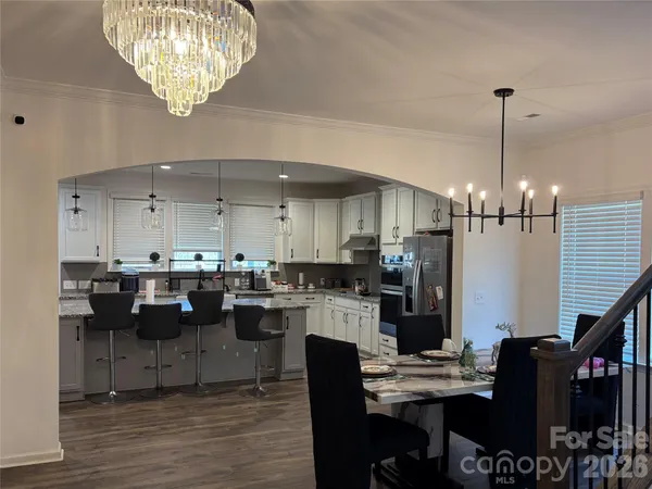 a kitchen with stainless steel appliances kitchen island granite countertop a table chairs and a refrigerator