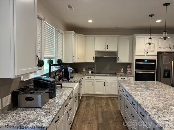 a kitchen with kitchen island granite countertop a sink stove and cabinets