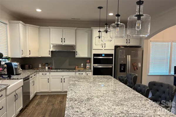 a kitchen with kitchen island granite countertop a stove a sink a refrigerator and cabinets